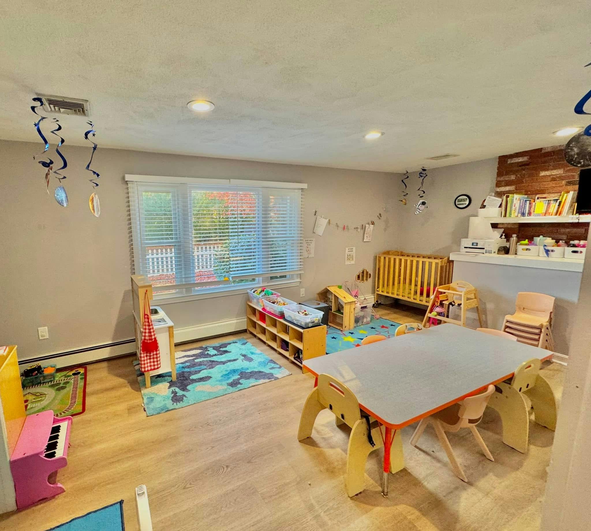 Playroom with a small table and chairs, crib, and toy shelves