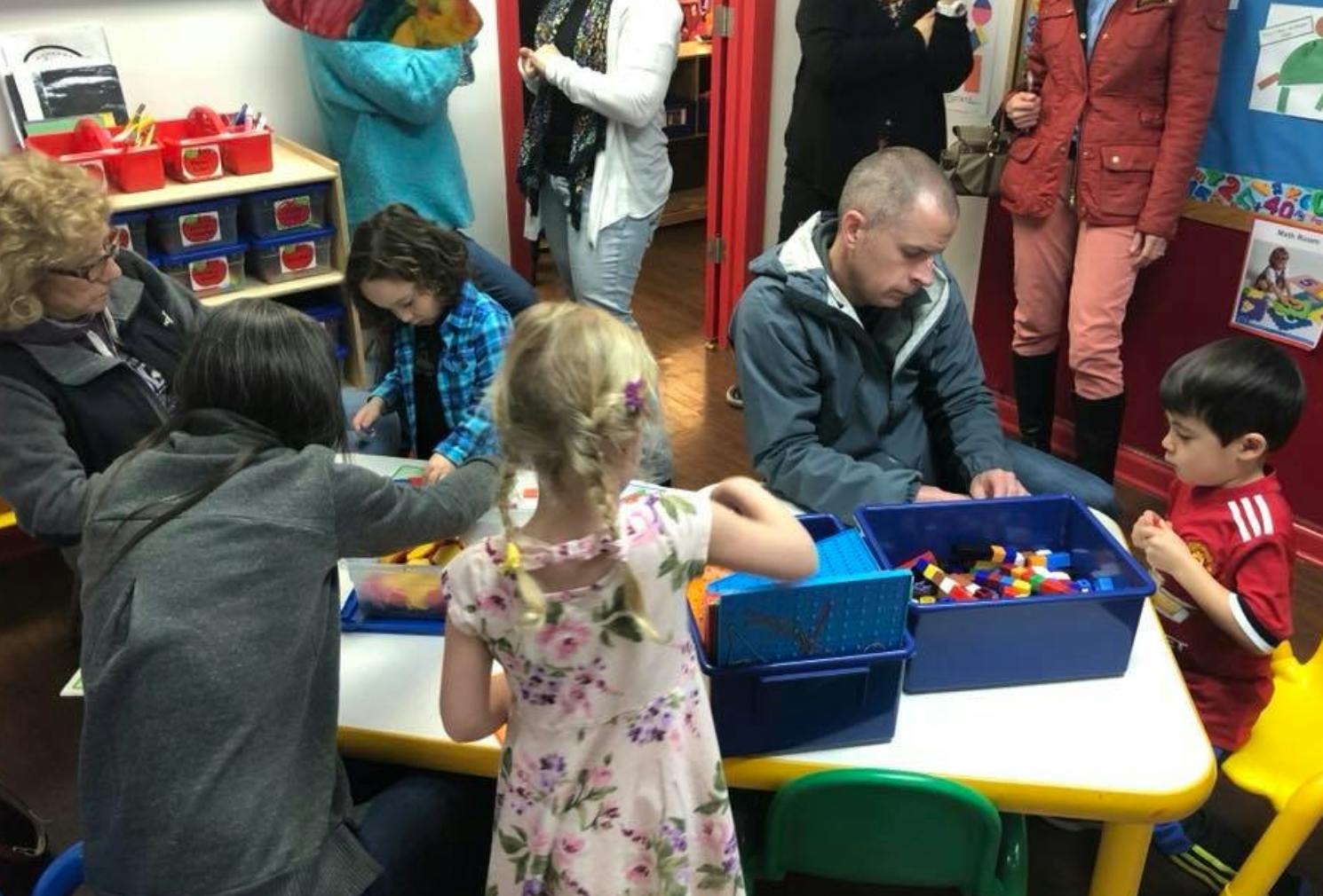 Adults and children playing with building blocks at a table