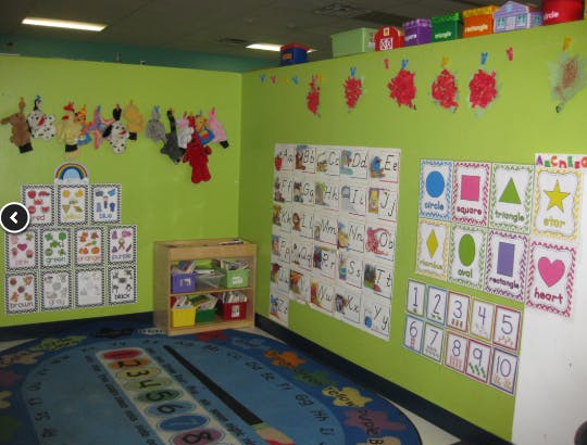 Classroom with green walls, educational posters, and a blue rug