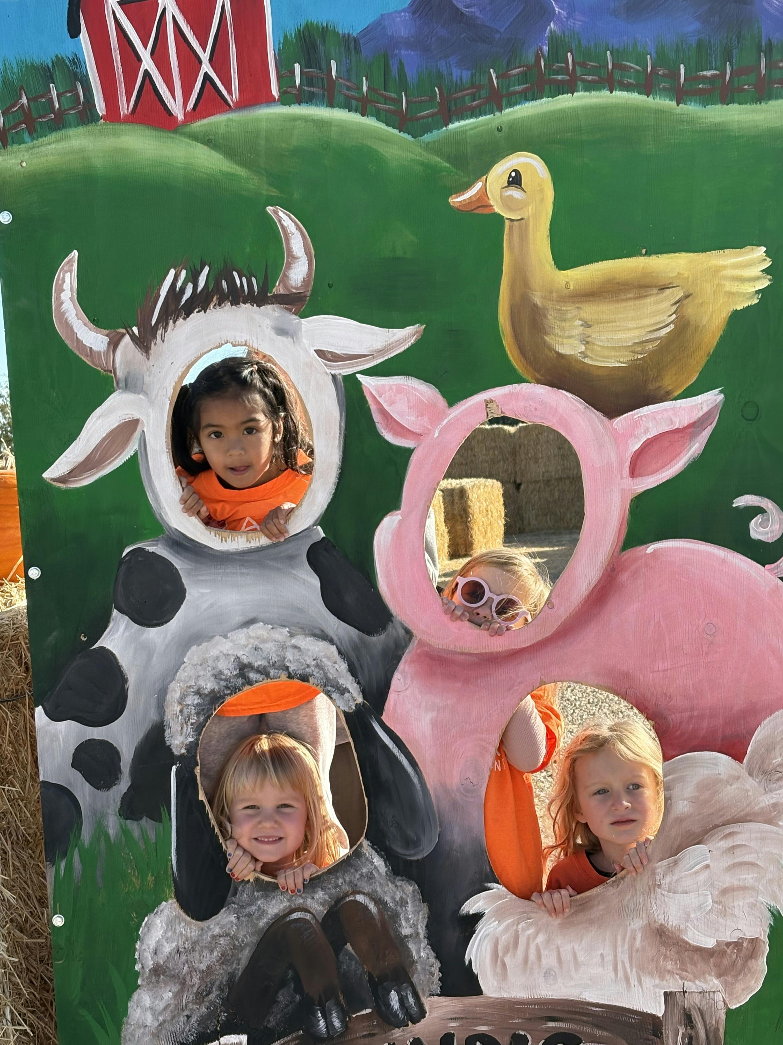 Four children in a farm animal photo cutout board