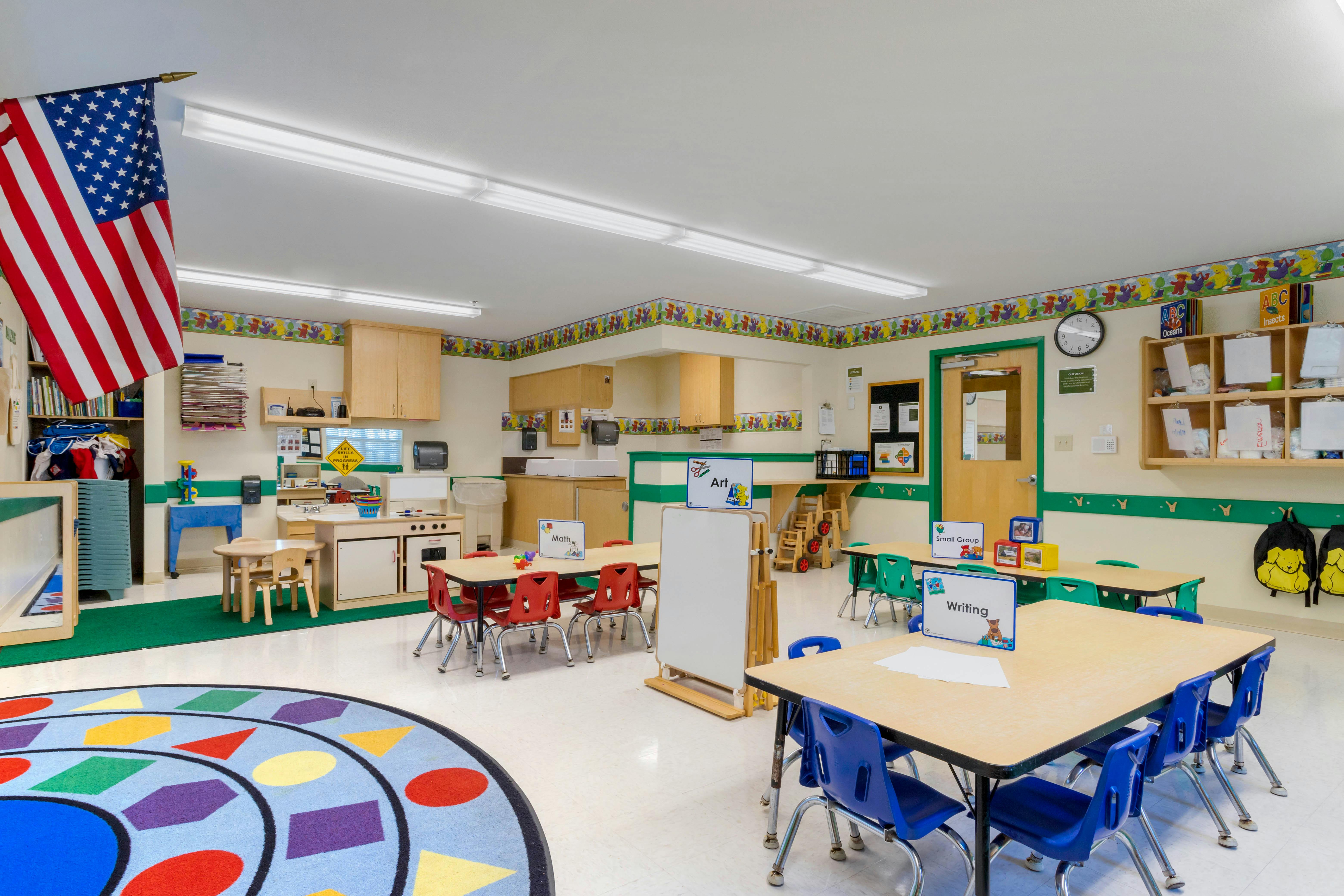 Empty classroom with small tables, chairs, and learning stations