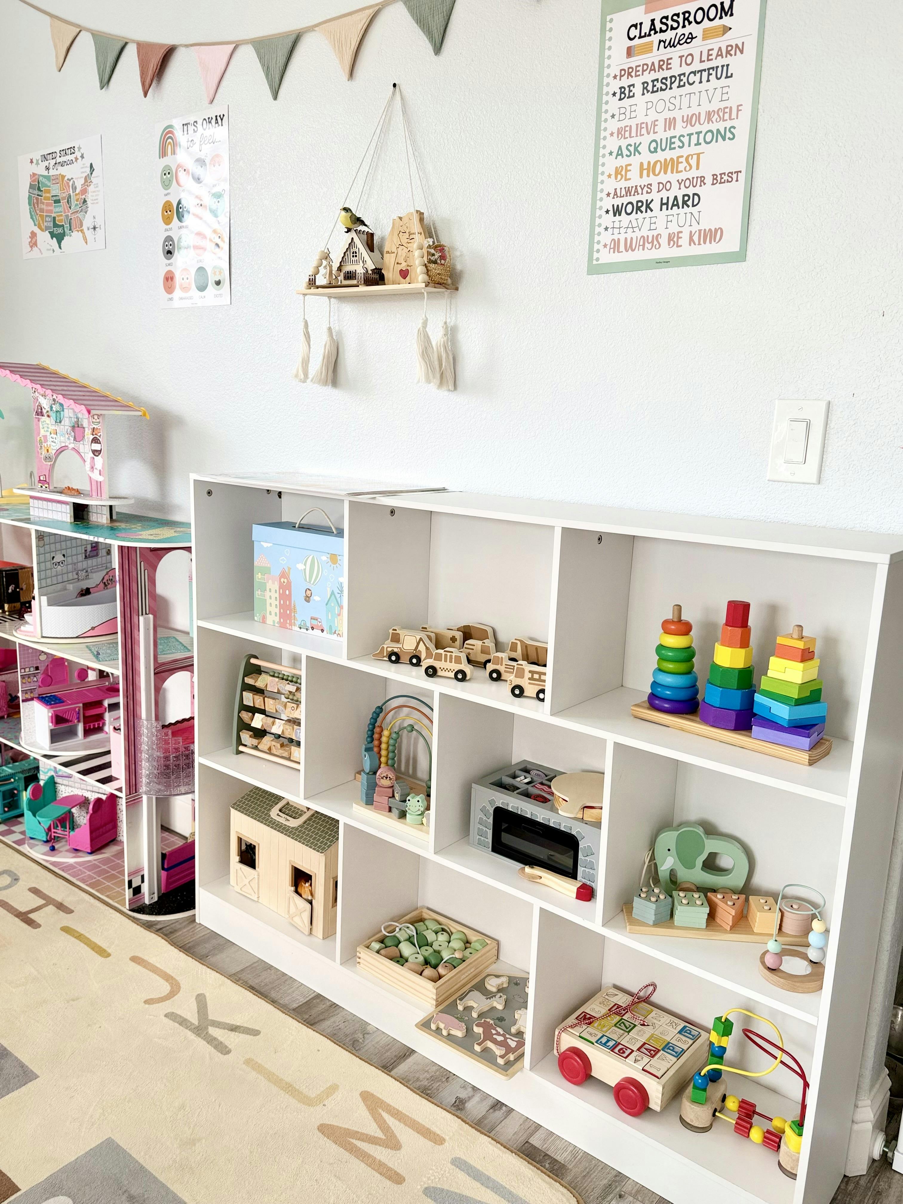 Dollhouse and white shelving unit filled with educational wooden toys