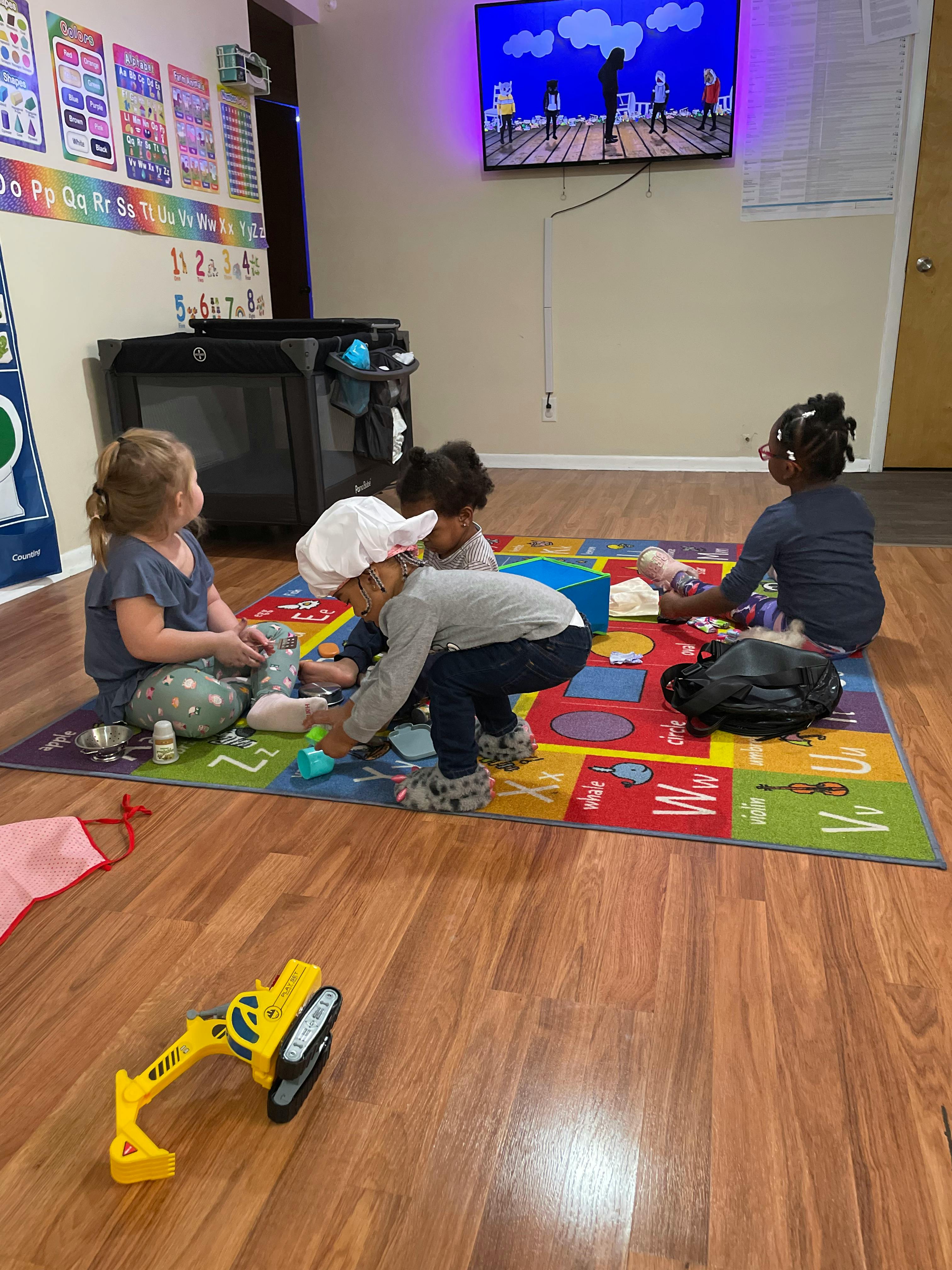 Children playing on a colorful mat in a room with a TV