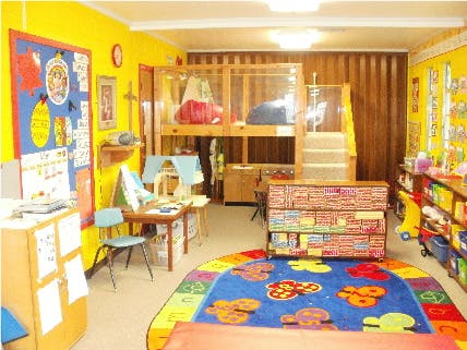 Classroom with a play loft, colorful rug, and shelves of toys