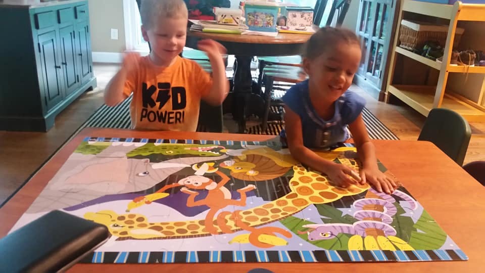 Two children playing with a large floor puzzle