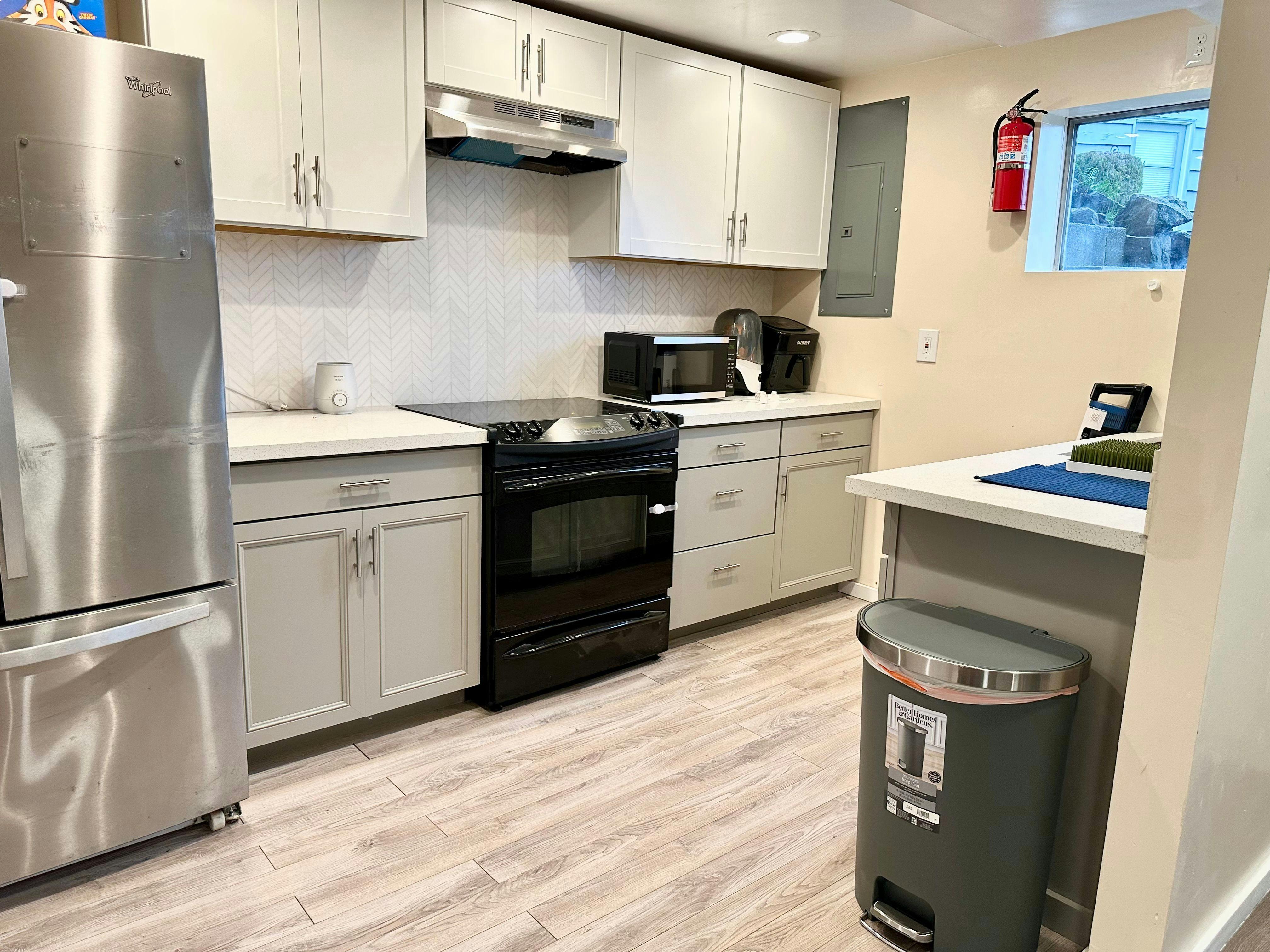 Kitchen with stainless steel refrigerator, black stove, and light cabinets