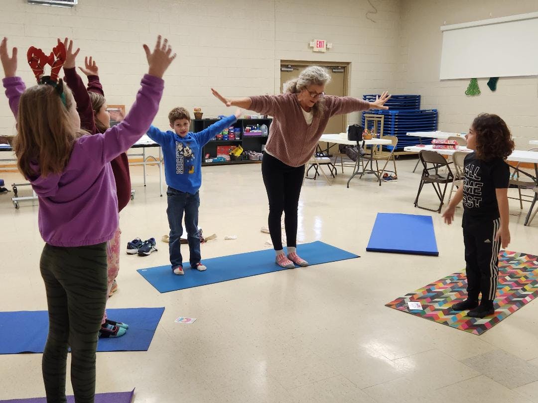 Adult and children doing yoga poses on mats in a room