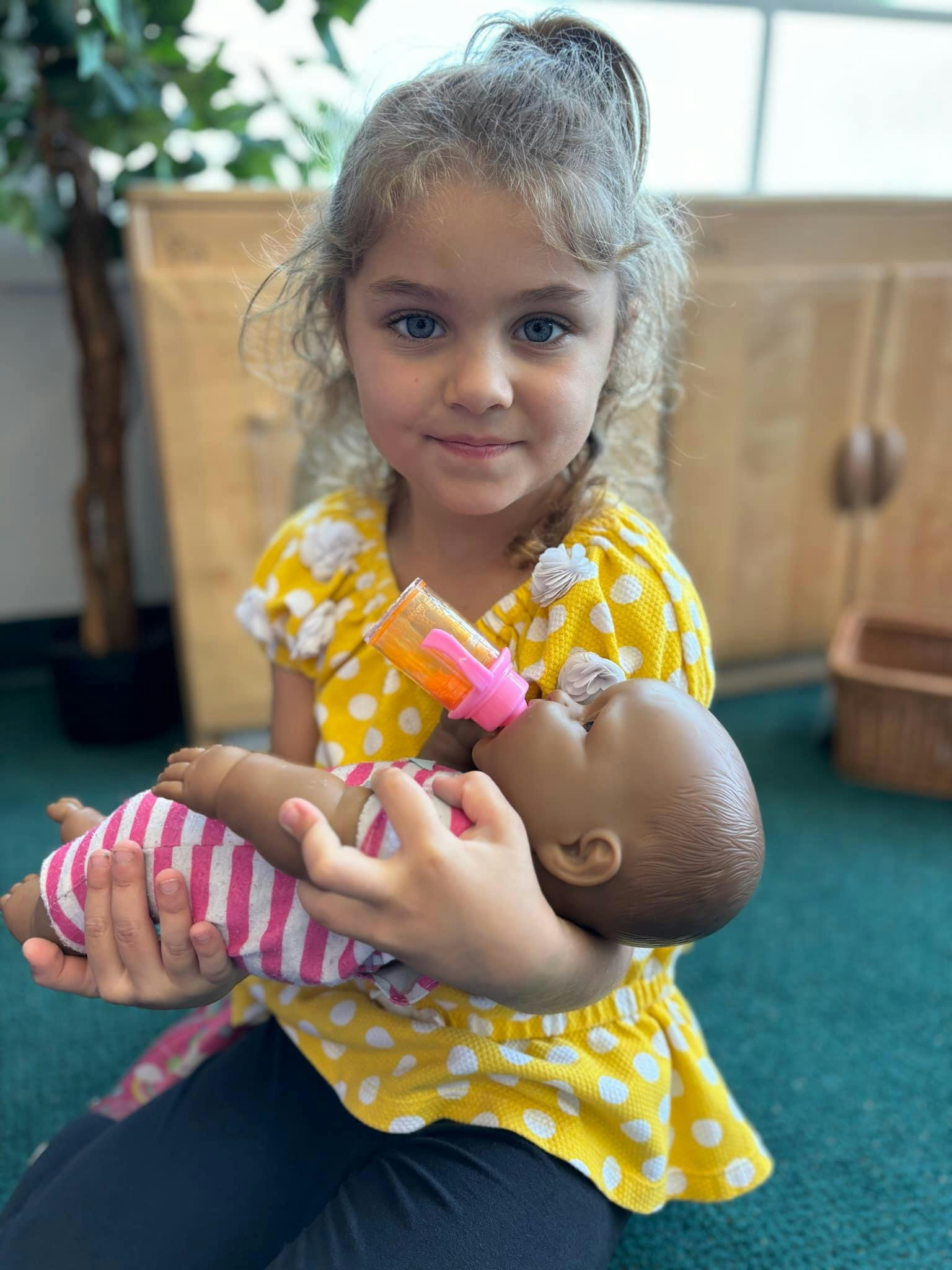 Child holding and feeding a baby doll with a bottle