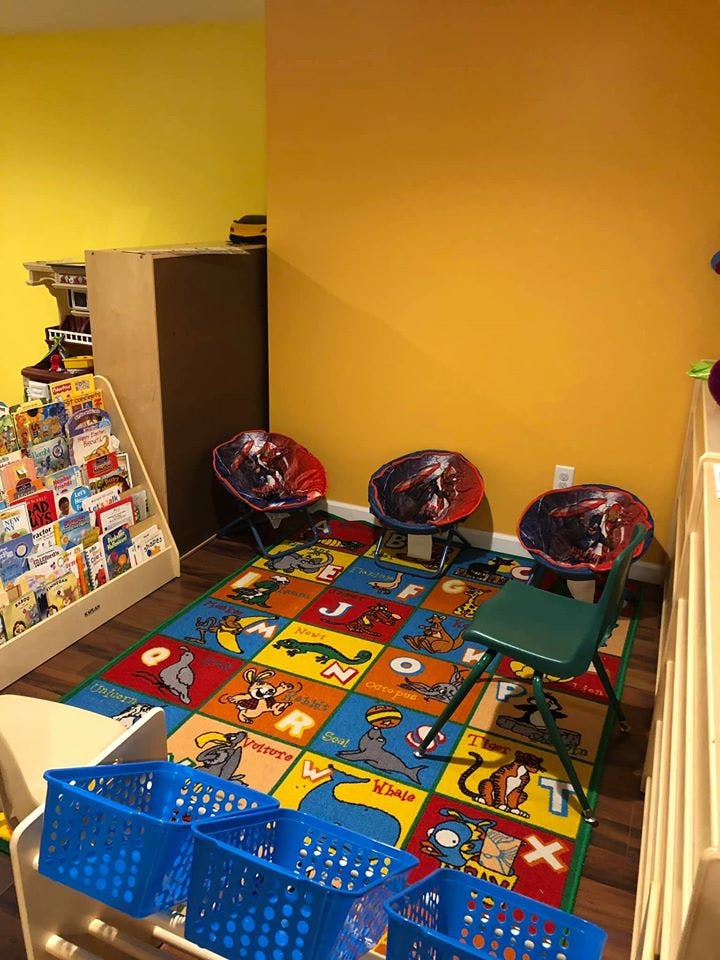 Children's play area with alphabet rug, small chairs, and book display