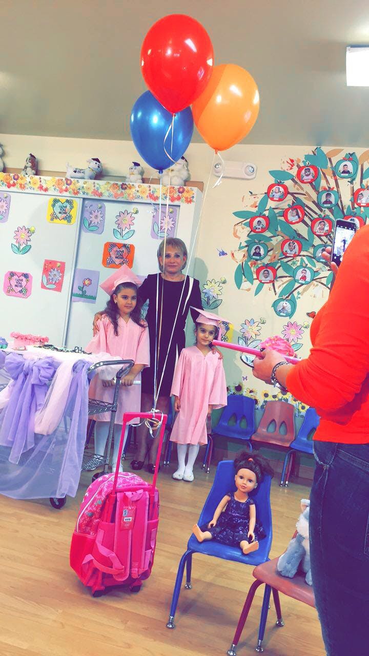 Adult and two children in graduation gowns posing with balloons