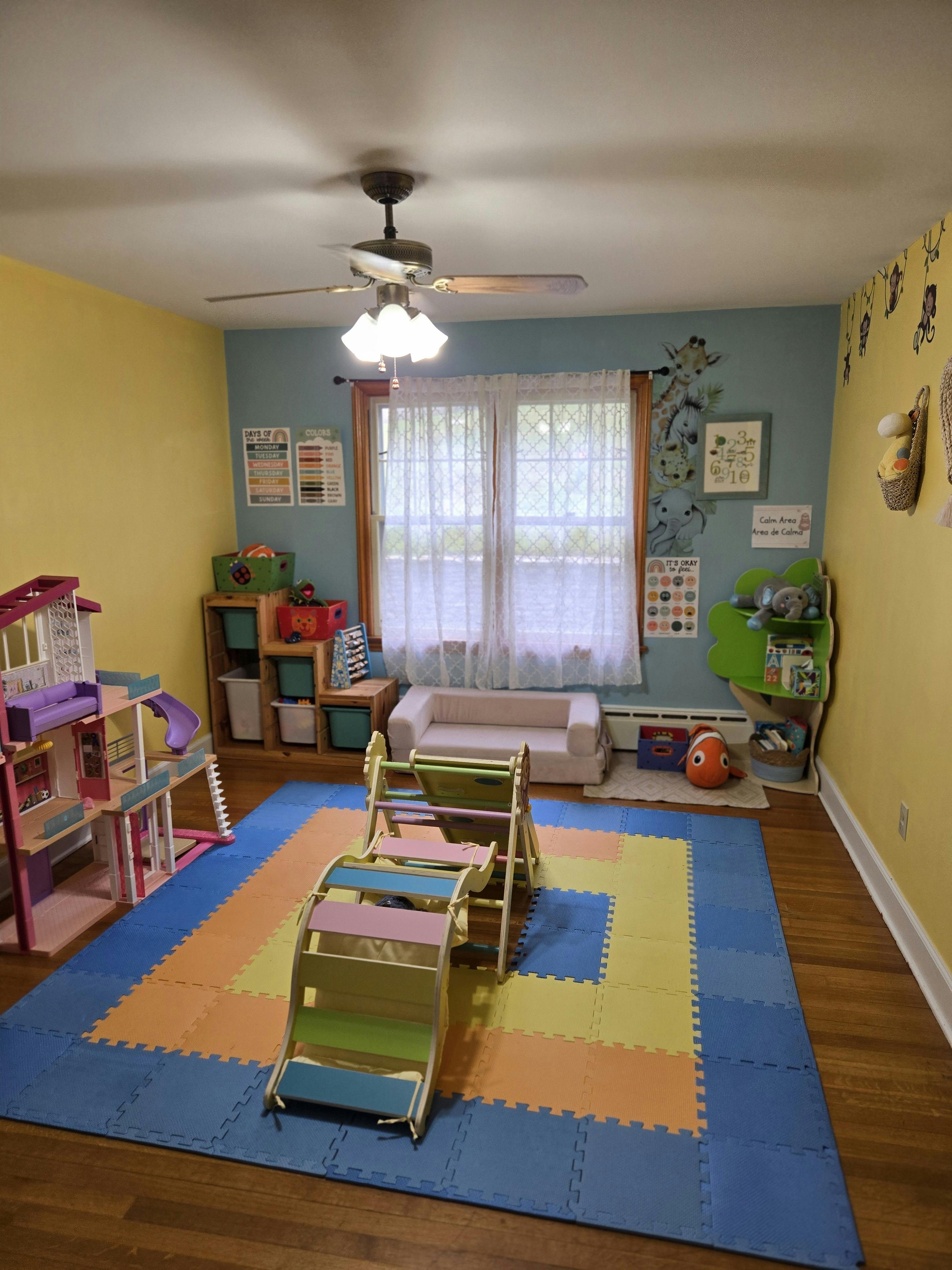 Playroom with colorful floor mats, dollhouse, and climbing structure