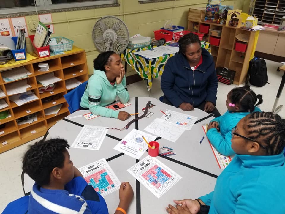 Adults and children sitting around a table with papers and art supplies