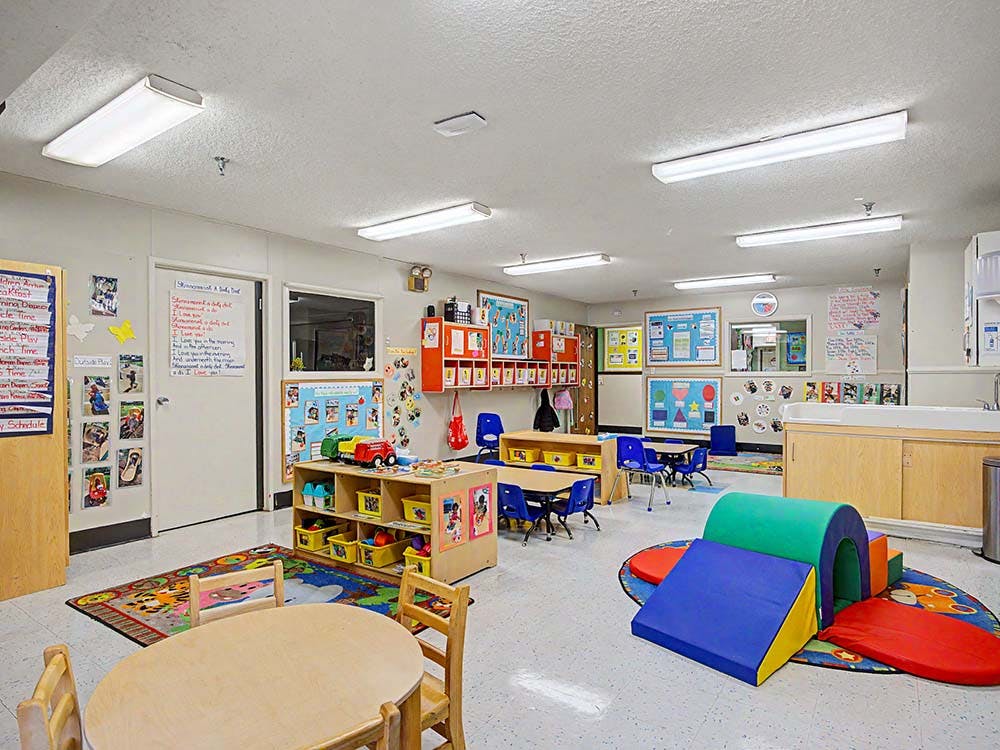 Child care classroom with tables, chairs, and soft play equipment
