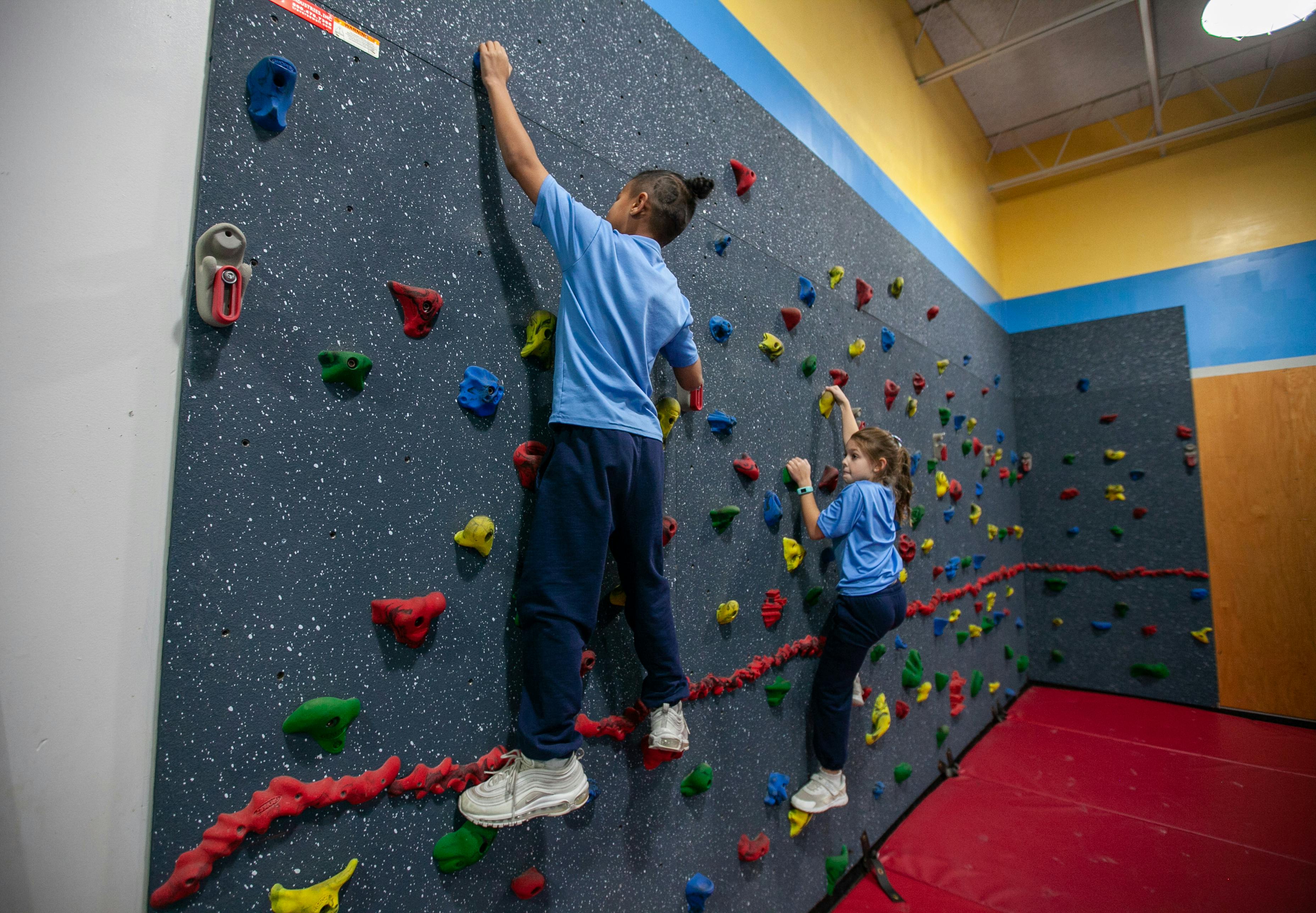 Two people climbing on an indoor rock wall