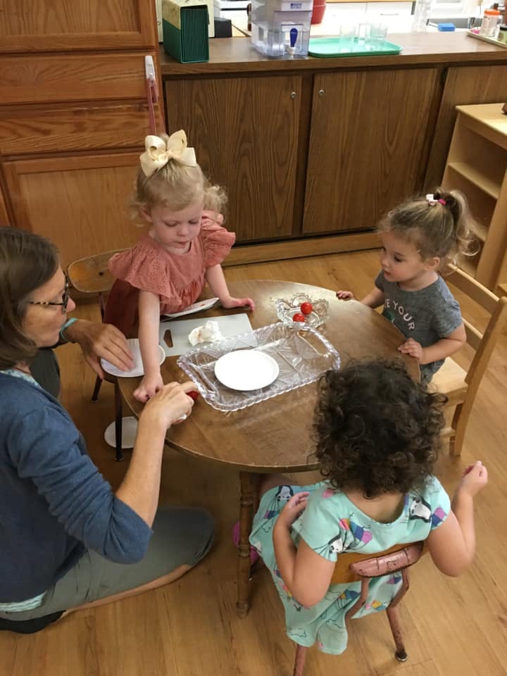 Adult and three children at a table with a tray of food items