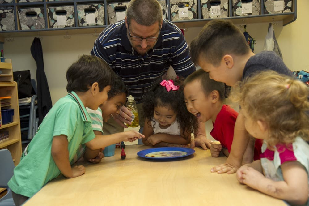 Adult and children gathered around a table looking at a plate
