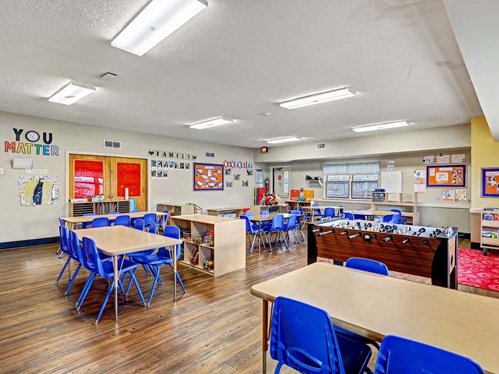 Classroom with tables, chairs, foosball table, and student artwork on the walls
