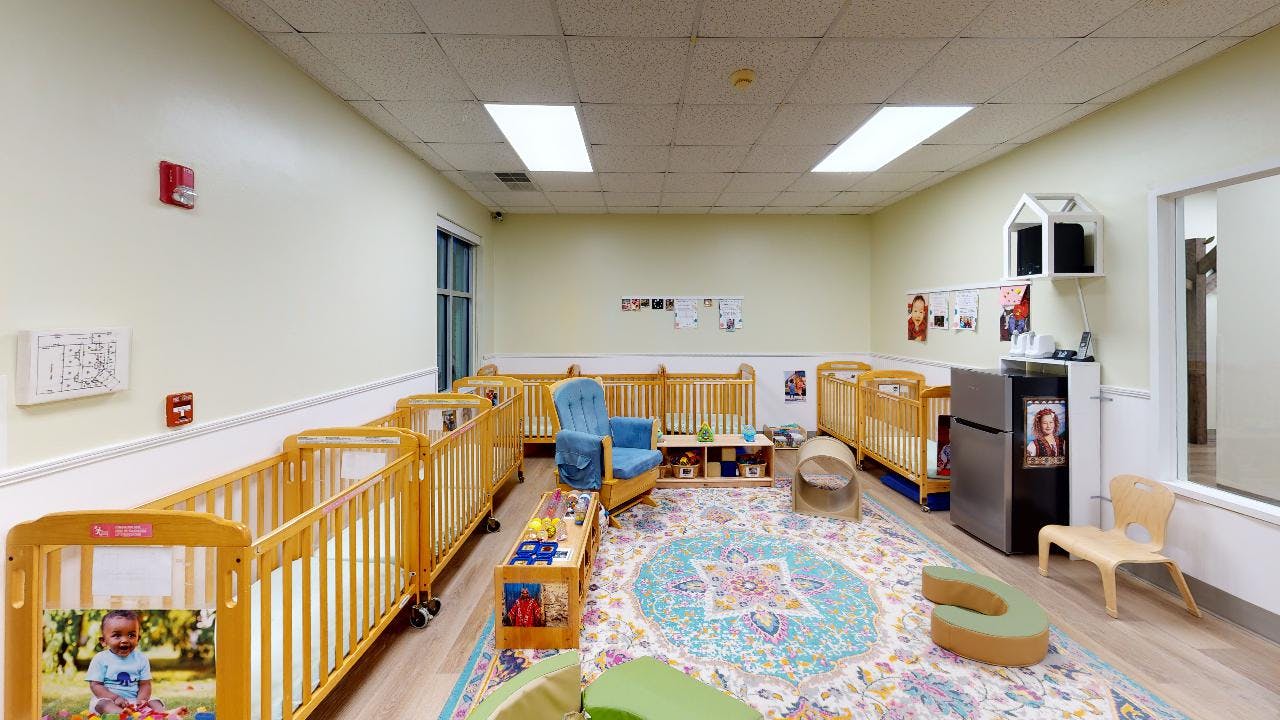 Nursery room with multiple cribs and a colorful rug