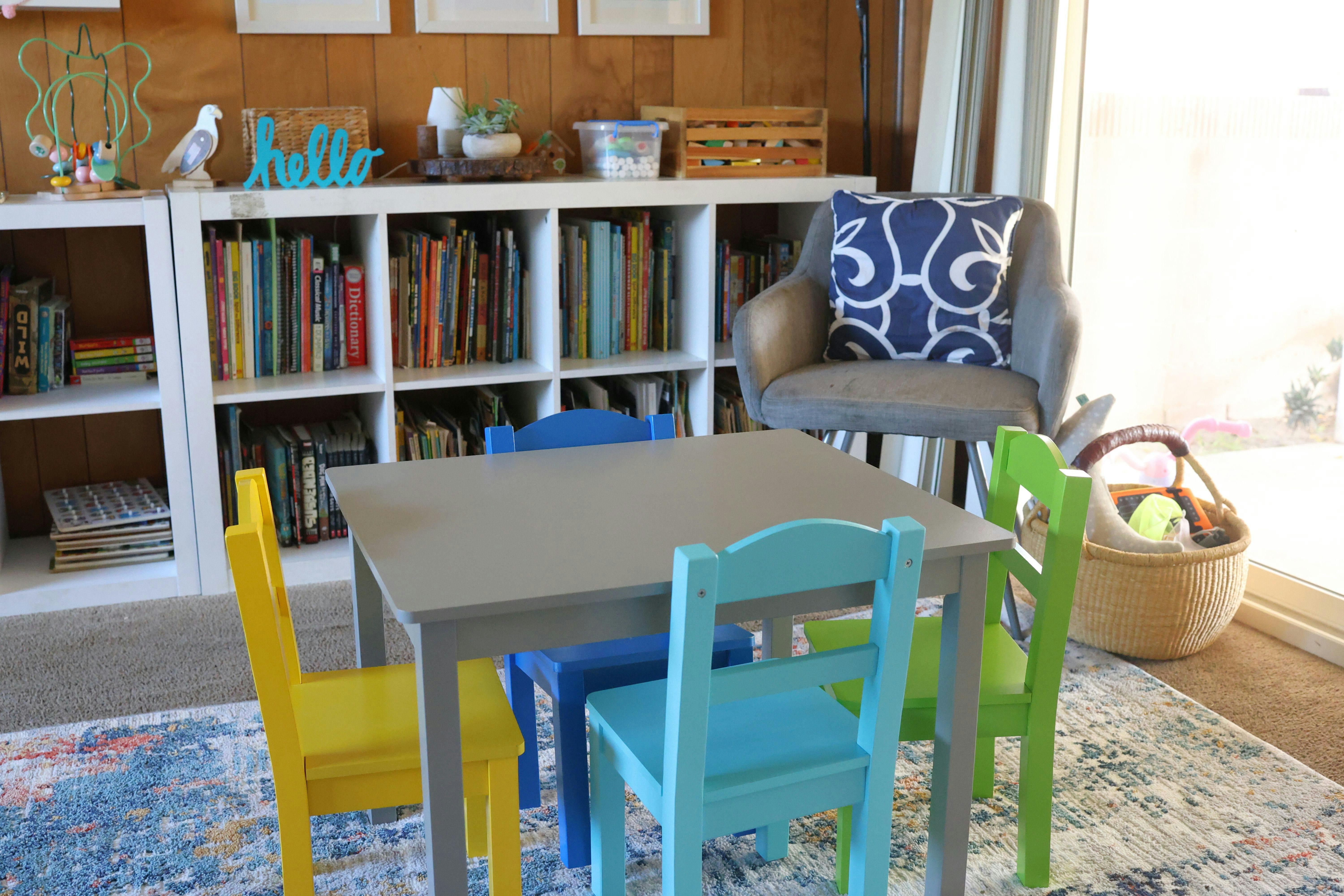 Small table with colorful chairs in a room with bookshelves