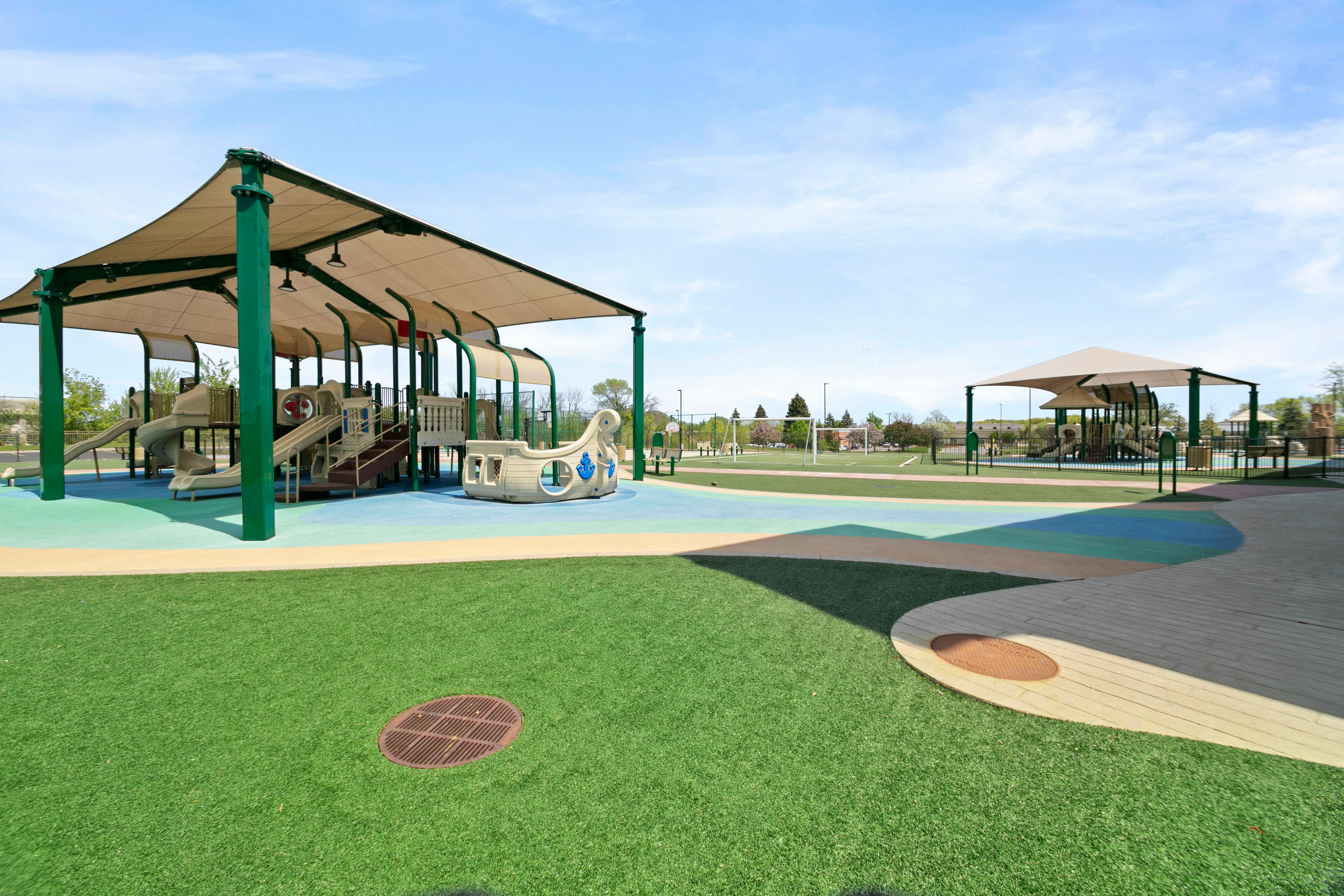 Playground with climbing structures, slides, and a play ship under shaded canopies