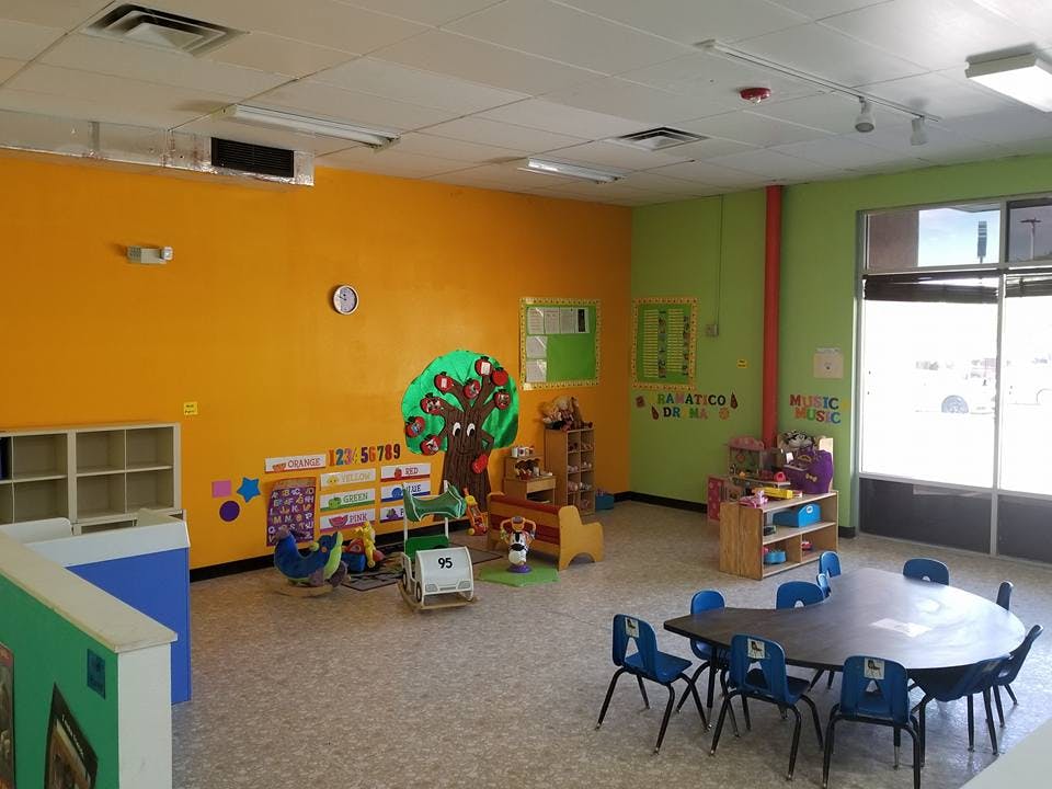 Classroom with colorful walls, small tables and chairs, and play areas