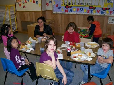 Adult and children eating at a table in a classroom