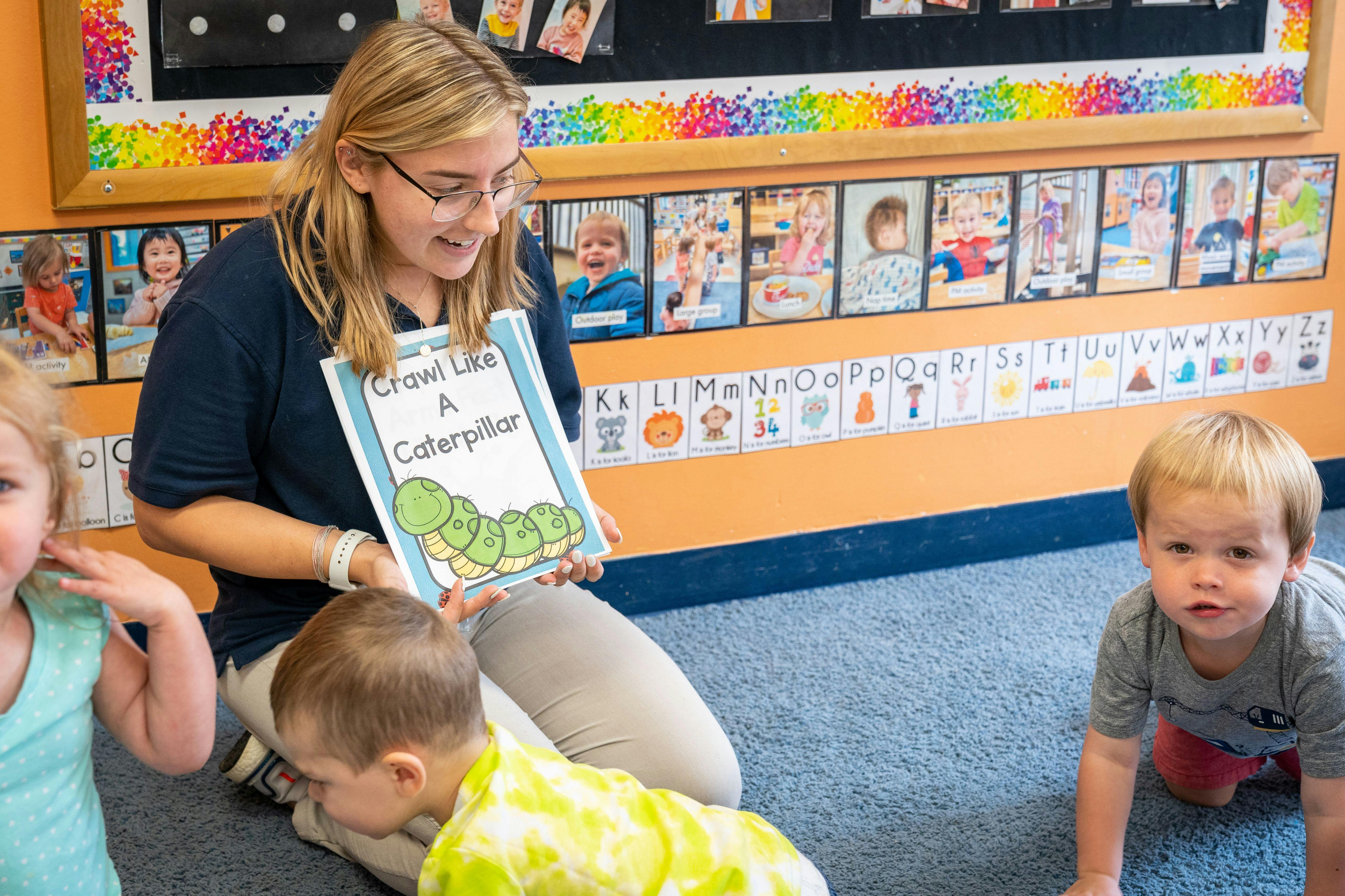 Person holding a book titled "Crawl Like A Caterpillar" to children