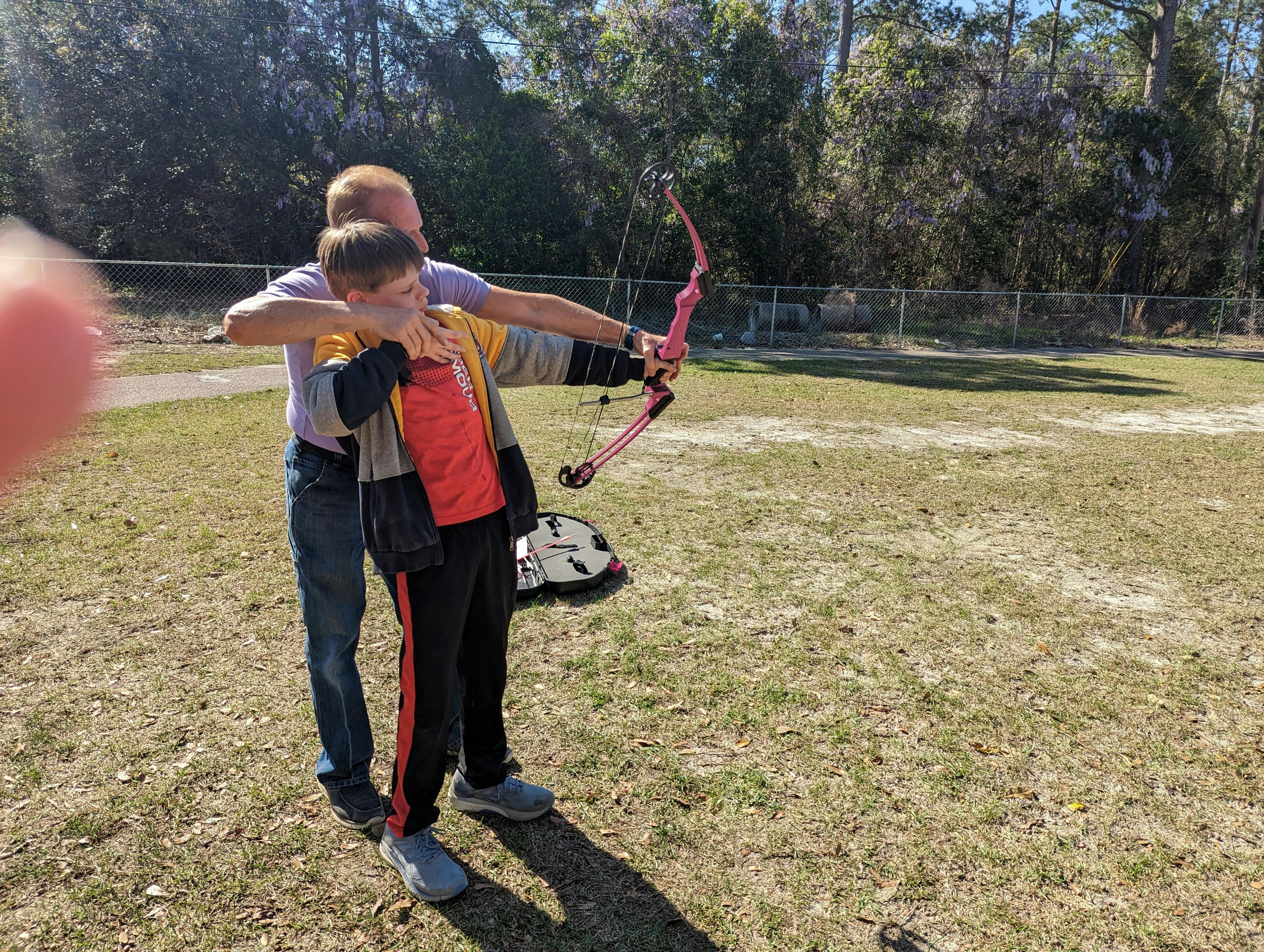 Adult and child aiming a pink bow