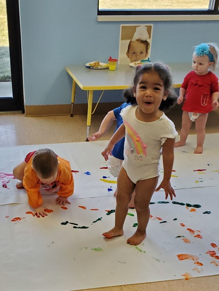 Children playing with paint on a large sheet of paper