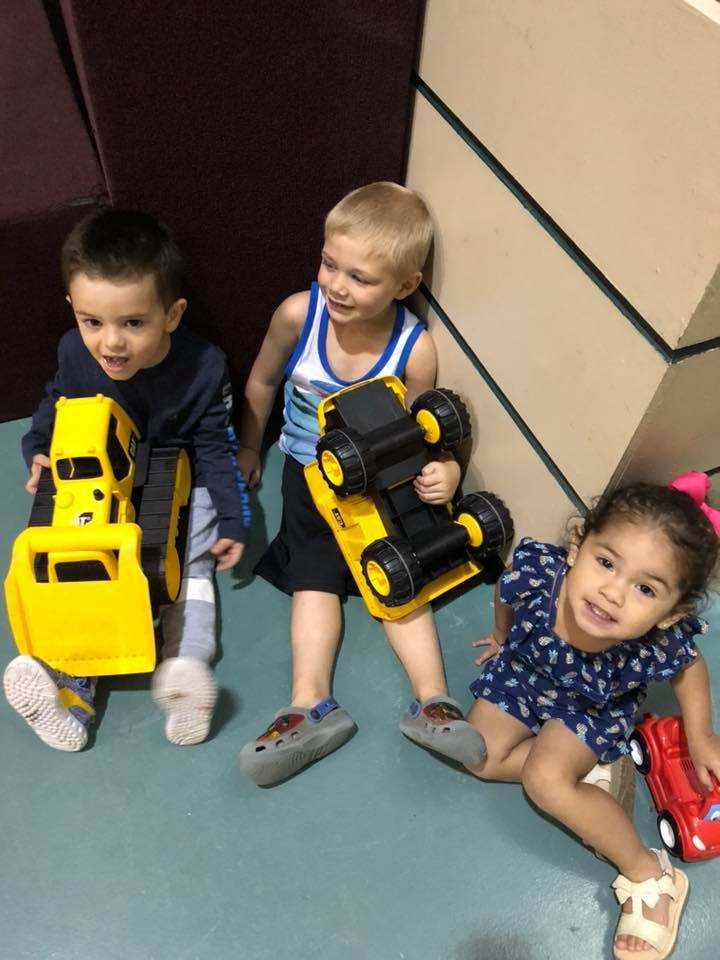Three children playing with toy trucks