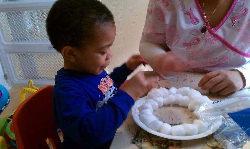 Child and person crafting with cotton balls