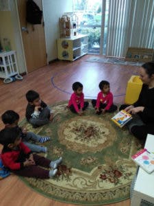 Adult reading a book to children sitting in a circle on a rug