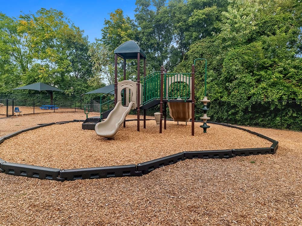 Outdoor playground with a slide, climbing structure, and wood chip ground