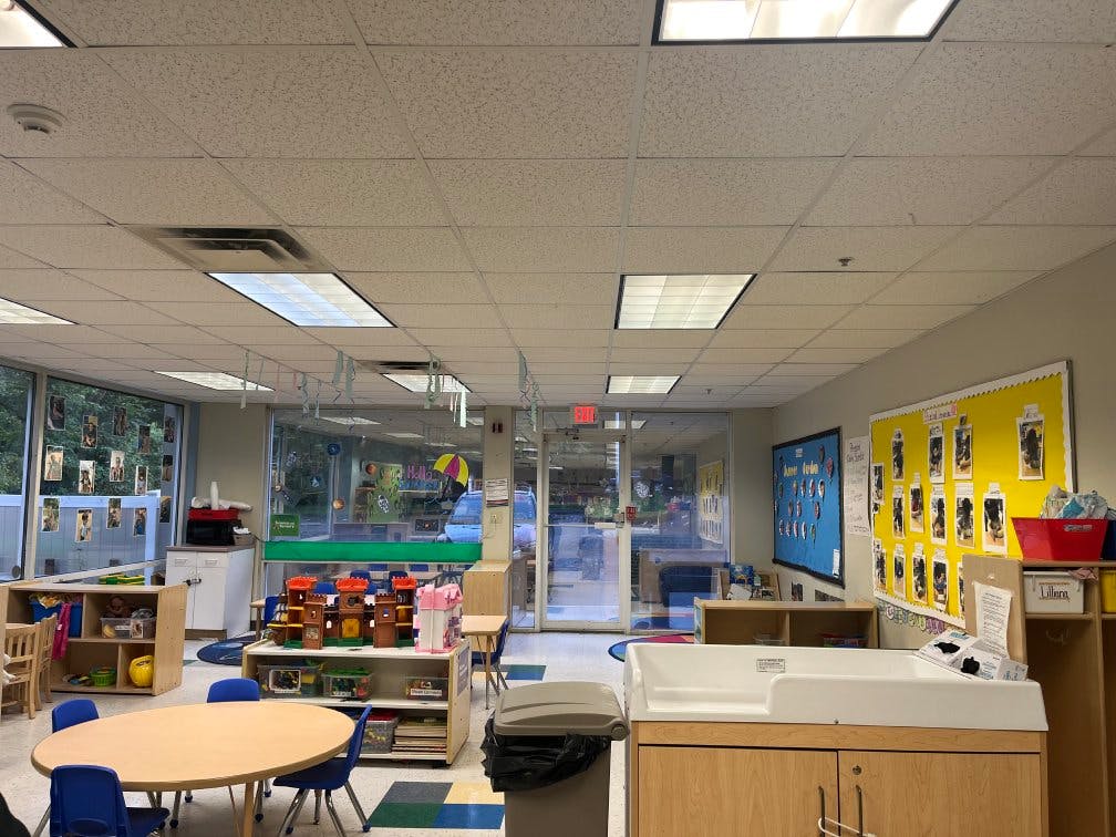 Classroom with child-sized tables, chairs, toys, and bulletin boards