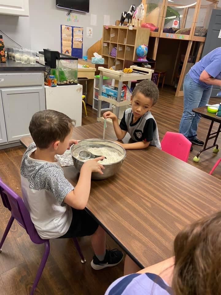 Two children at a table with a large bowl of white mixture