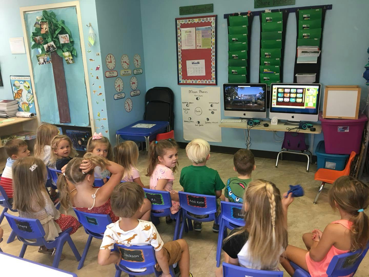 Children sitting in chairs in a classroom looking at computer screens