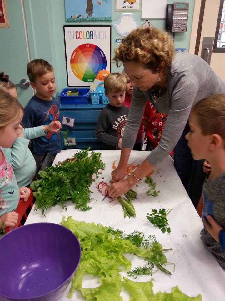 Adult and children preparing vegetables on a table