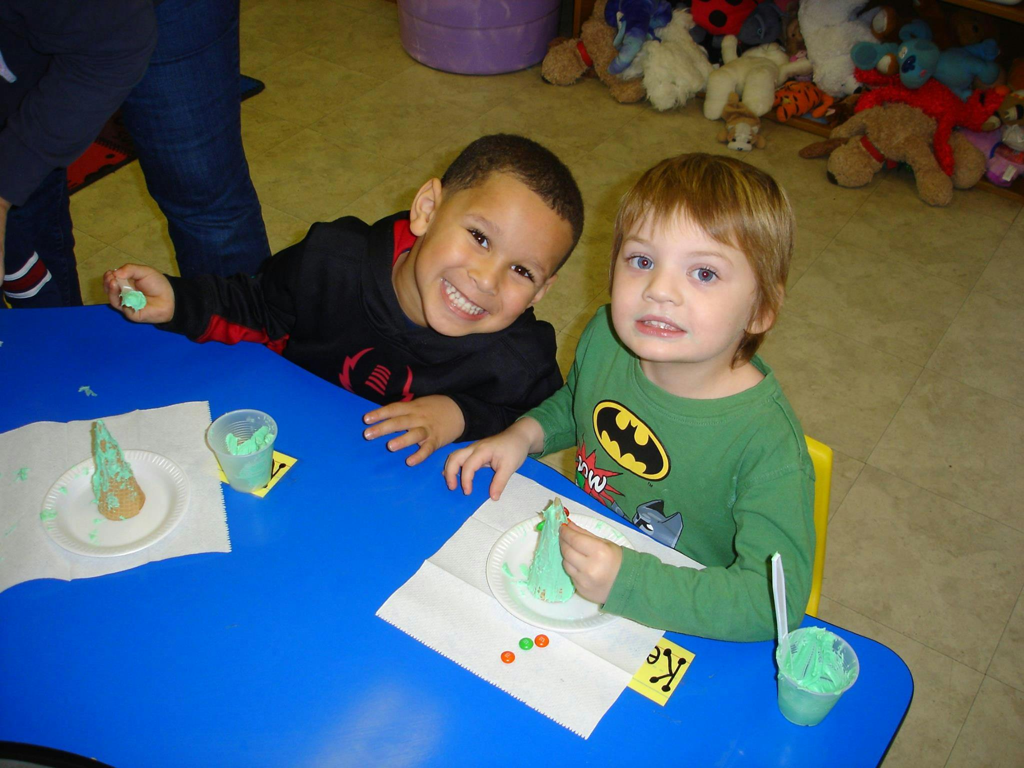 Two children at a blue table with green playdough creations