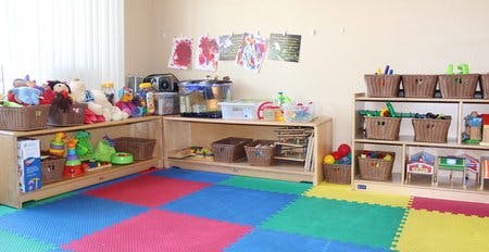Classroom with shelves of toys and baskets on a colorful mat floor