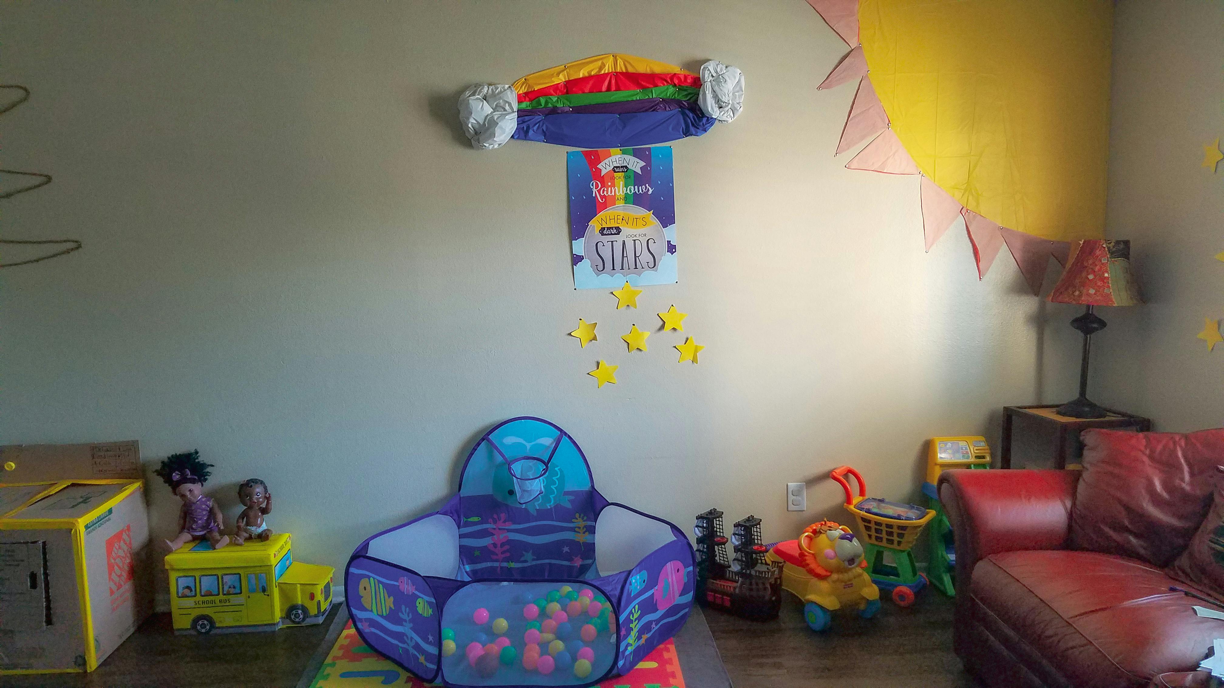 Playroom with a ball pit, toys, and rainbow wall decor