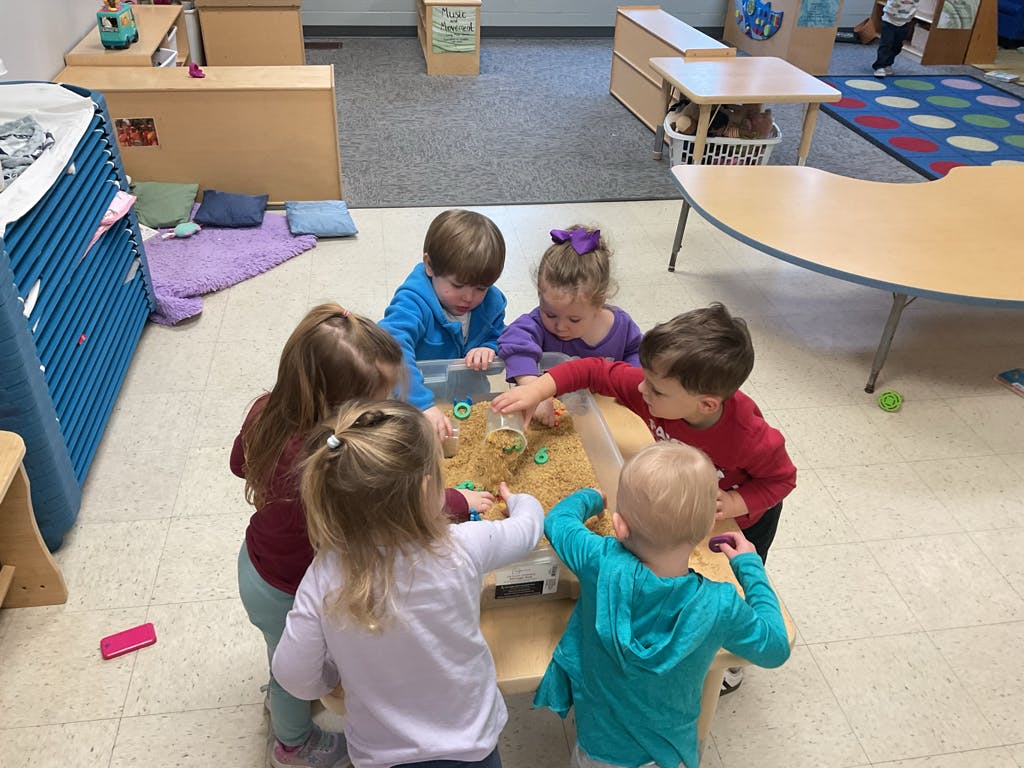 Five children playing around a sensory table
