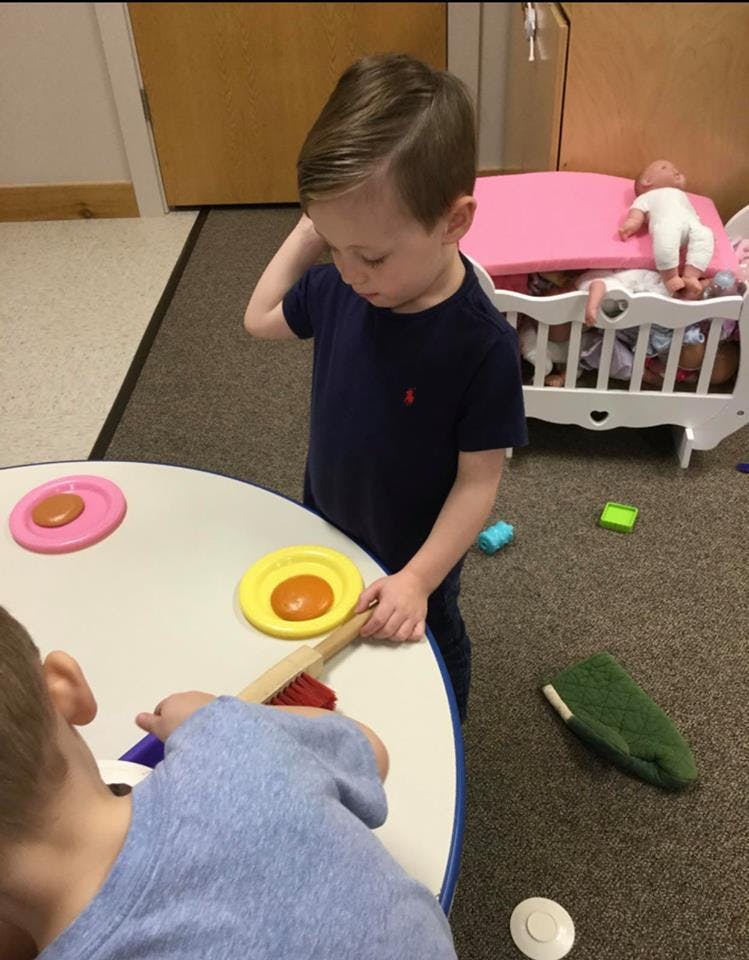 Child playing with toy food and brush at a table