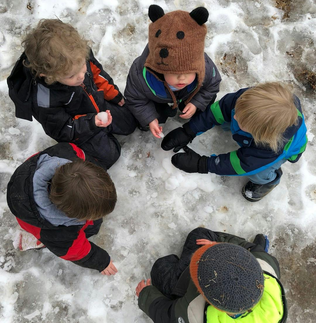 Four children sitting in a circle on snow