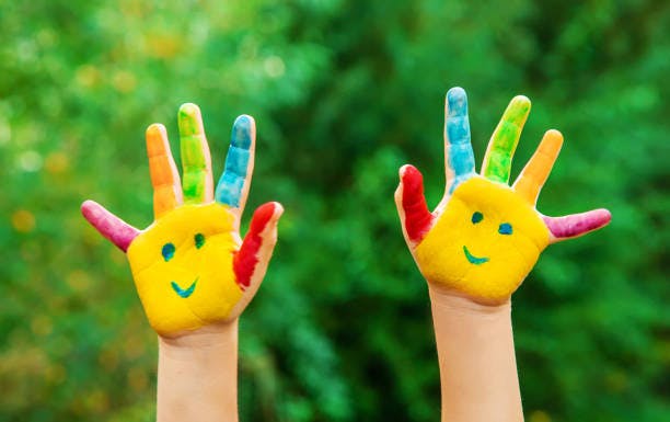 Two hands painted with colorful fingers and smiling faces on palms
