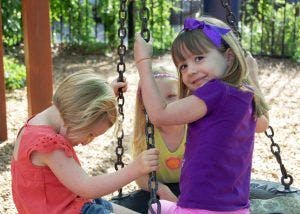 Three children on a tire swing