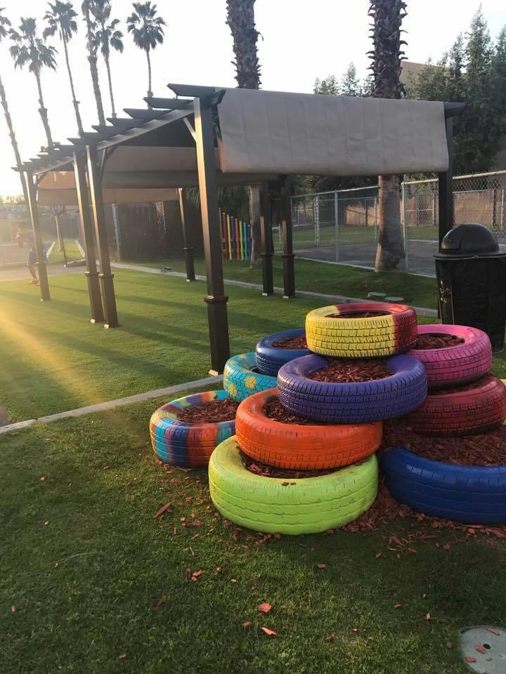 Stack of colorful painted tires filled with mulch on grass