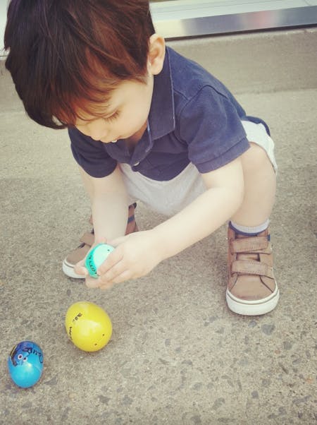 Child crouching and holding a small egg-shaped toy