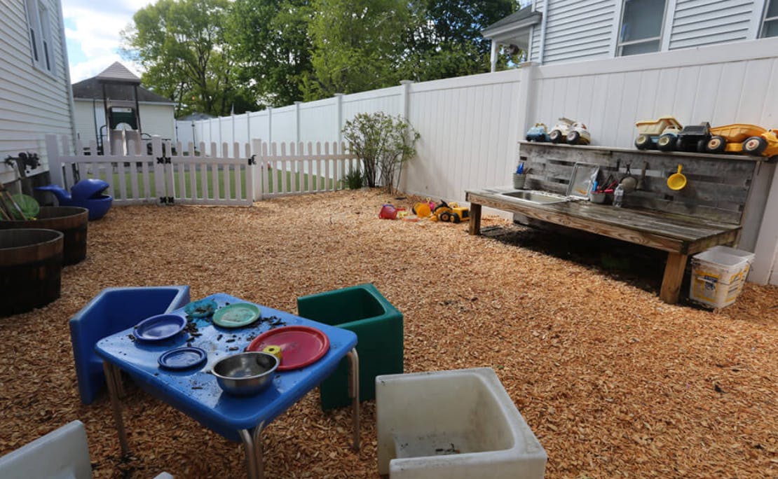 Outdoor play area with wood chips, a small table, and a wooden play kitchen