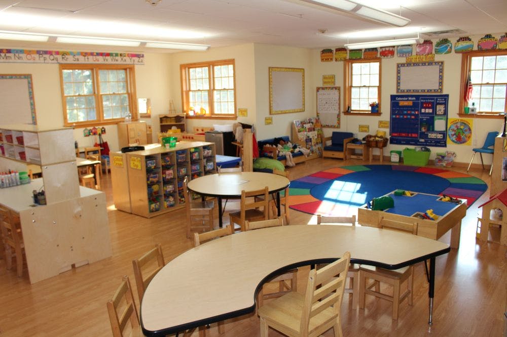 Empty classroom with tables, chairs, and colorful rug
