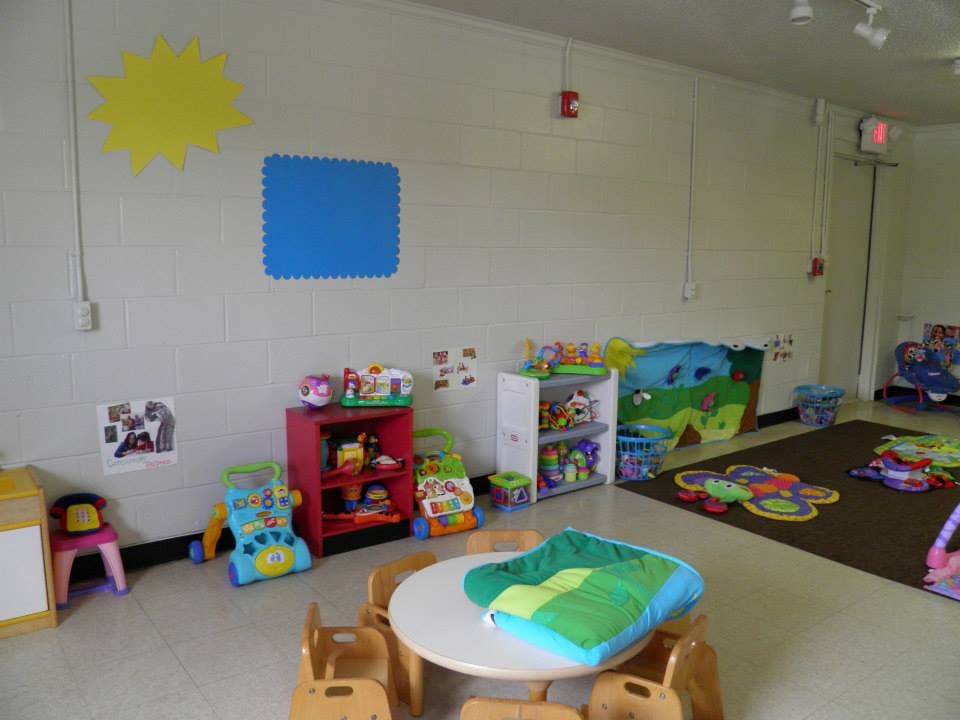Playroom with small table and chairs, shelves of toys, and play mats